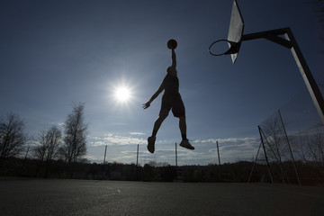 Silhouette basketball player in mid air slam dunking