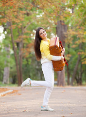 Beautiful brunette girl with suitcase in the park.