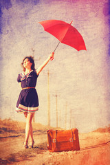 Beautiful brunette girl with suitcase and umbrella on the countr