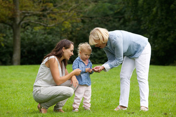 Mother and grandmother showing little girl flower