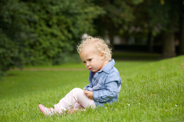 Cute little girl sitting on green grass outdoors