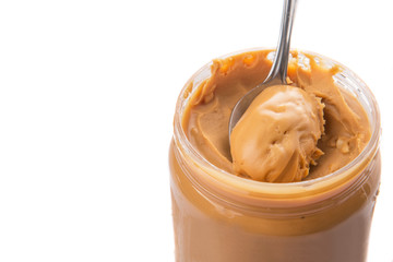 An opened jar of peanut butter with a small spoon