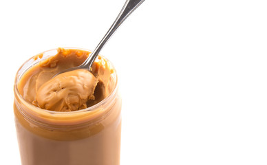 An opened jar of peanut butter with a small spoon