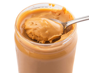 An opened jar of peanut butter with a small spoon