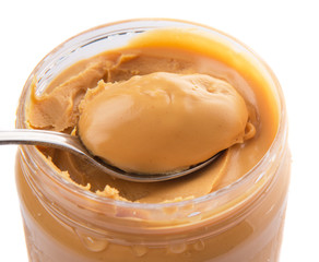 An opened jar of peanut butter with a small spoon