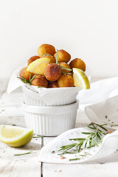 balls of fried potatoes with lemon slice and rosemary on table