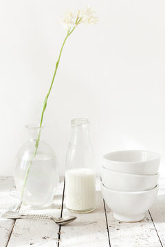 tuberose flower on glass, three bowls and bottle of milk