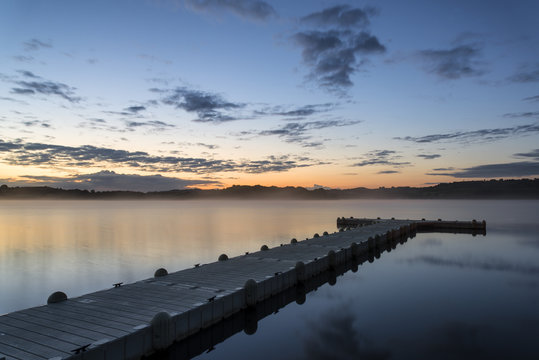 Sunrise vibrant landscape of jetty on calm lake