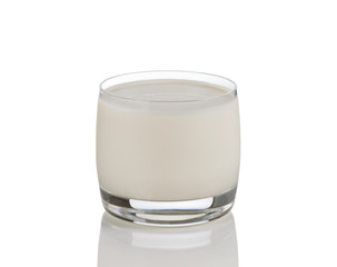 Full glass of fresh milk on white with reflection