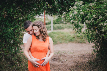 Young pregnant woman with her husband holding hands on her belly