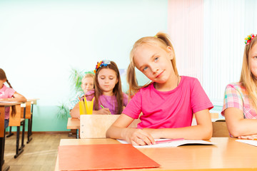 Fototapeta premium Girl sits at desk with elbows on exercise book