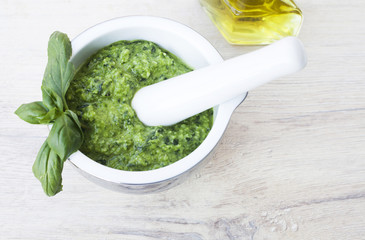 basil pesto in ceramic bowl on wooden background