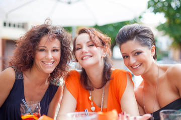 Happy young girl friends having fun in a bar drinking cocktail.