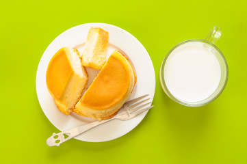 Custard cake and milk on green background.