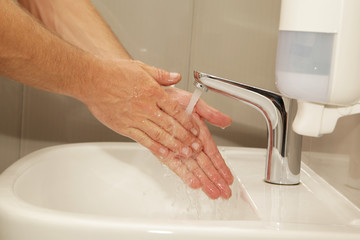 Hands under running water in the sink