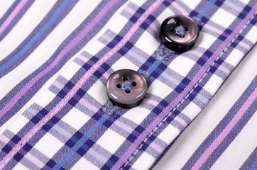 Close-up of buttons on a striped purple shirt.