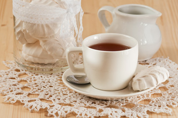 Cup of tea with cinnamon and marshmallows on the lace napkin