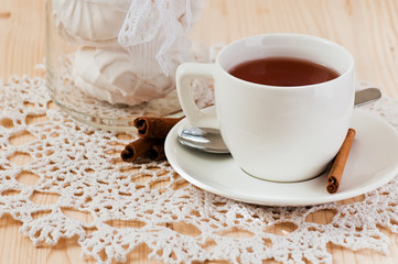 Cup of tea with cinnamon and marshmallows on the lace napkin