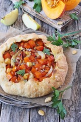 Pumpkin-apple galette with onion and bacon on a wooden table