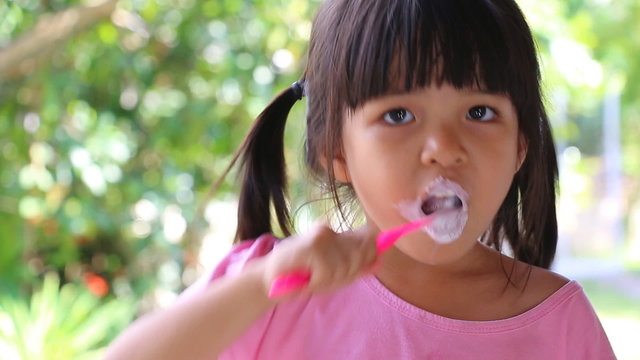 Cute Asian Girl Brushing Teeth (With Toothpaste)