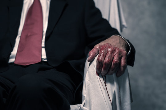 Bloody hand of businessman sitting in white chair.