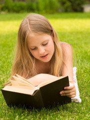 teenage girl lying on grass and read book