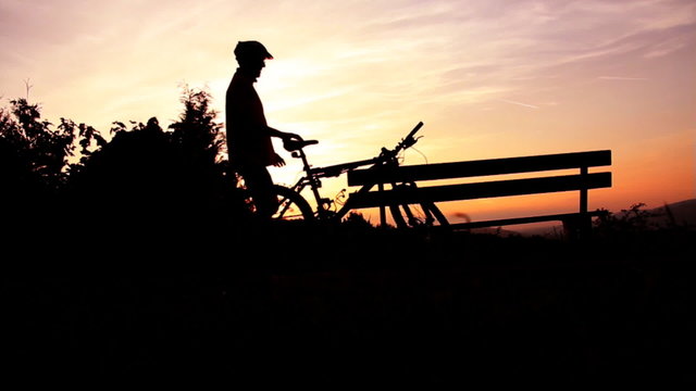 Fahrradfahrer fährt weg bei Sonnenuntergang