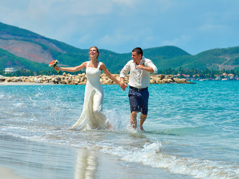 Happy Bride and groom running on a beautiful tropical beach