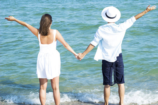 Couple holding hands on beach and looking on the sea