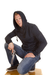 man in dark hoodie hold gun looking