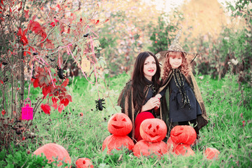 mother and daughter with pumpkins dressed as witches outdoor
