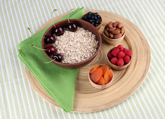 Big round wooden plate with raisins, raspberries, oatmeal, nuts