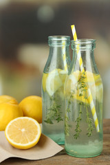 Tasty cool beverage with lemon and thyme, on light background