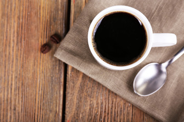 Cup of coffee and coffee beans on napkin on wooden background