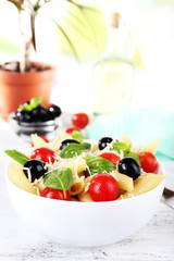 Pasta with tomatoes, olives and basil leaves in bowl