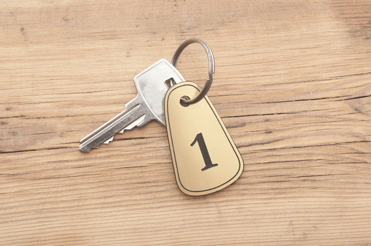Closeup of an key of room number 1 with key on a wooden desk