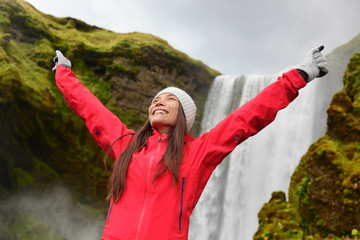 Naklejka premium Happy woman by waterfall Skogafoss on Iceland