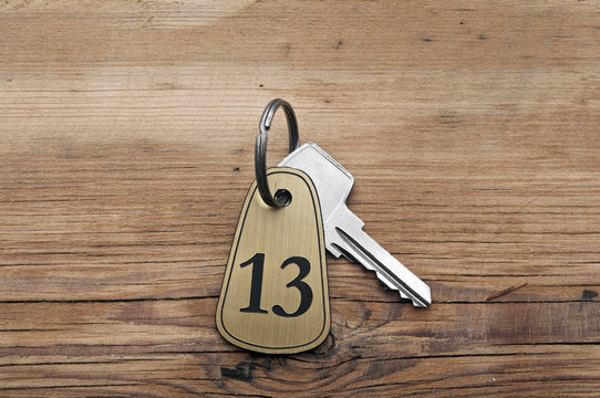 Closeup of an key of room number 13 with key on a wooden desk