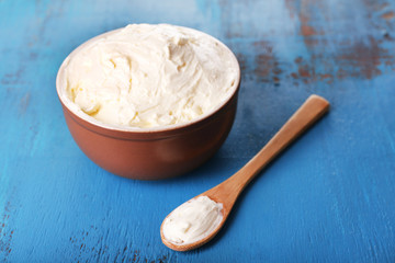 Fresh homemade butter in bowl, on color wooden background