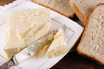Fresh butter on plate, on wooden background