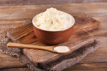 Fresh homemade butter in bowl, on wooden background
