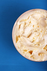 Fresh homemade butter in bowl, on color wooden background