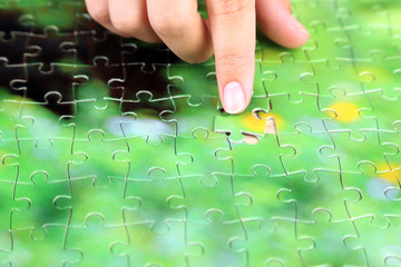 Hand holding puzzle piece on wooden table background