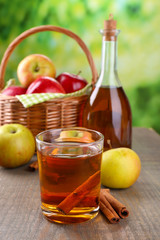 Apple cider in glass and bottle, with cinnamon sticks and fresh