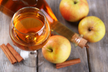 Apple cider in wine glass and bottle, with cinnamon sticks and