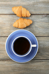 Breakfast with tea and fresh croissants on wooden background
