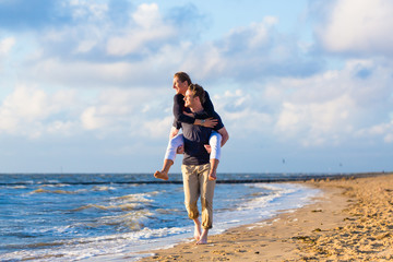 Mann trägt Frau huckepack am Strand