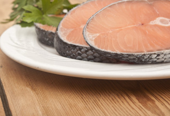 dish for baking with slices of salmon over wooden table