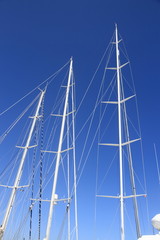 Three white yacht masts on blue sky