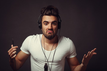 Handsome DJ posing in studio on dark background with headphones